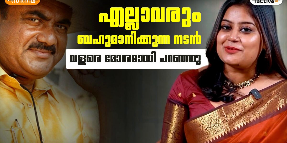 അൻസിബ ഹസൻ ചിരിക്കുന്നു, പിന്നിൽ ചുവന്ന പശ്ചാത്തലം