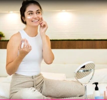 ഒരു യുവതി രാത്രികാല സ്കിൻകെയർ ഉൽപ്പന്നങ്ങൾ ഉപയോഗിച്ച് മുഖത്ത് പുരട്ടുന്നു