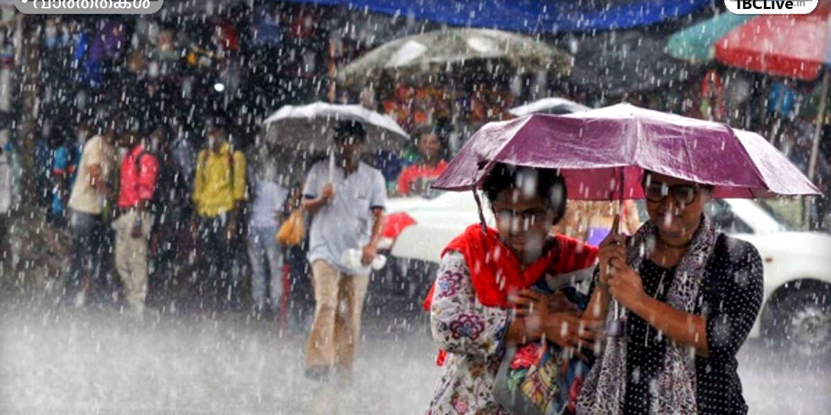 കേരളത്തിൽ മഴ പെയ്യുന്നതിൻ്റെ ചിത്രം, റോഡിലൂടെ വെള്ളം ഒഴുകുന്നു, ആളുകൾ കുട ചൂടി നടക്കുന്നു.
